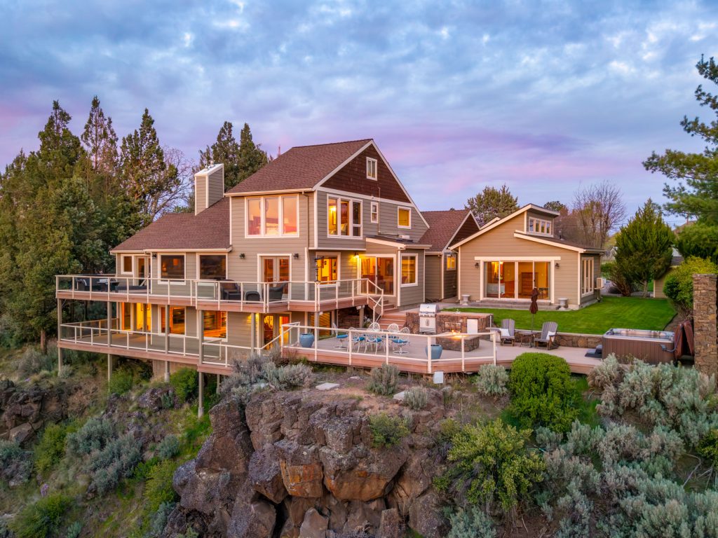Twilight canyon-edge home with wraparound deck in Bend, Oregon — real estate photography by Wasim