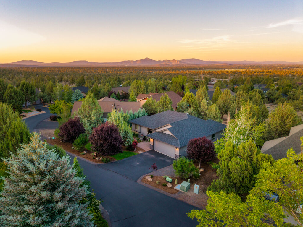 Golden-hour aerial photo of a Central Oregon home surrounded by pines and high-desert landscape